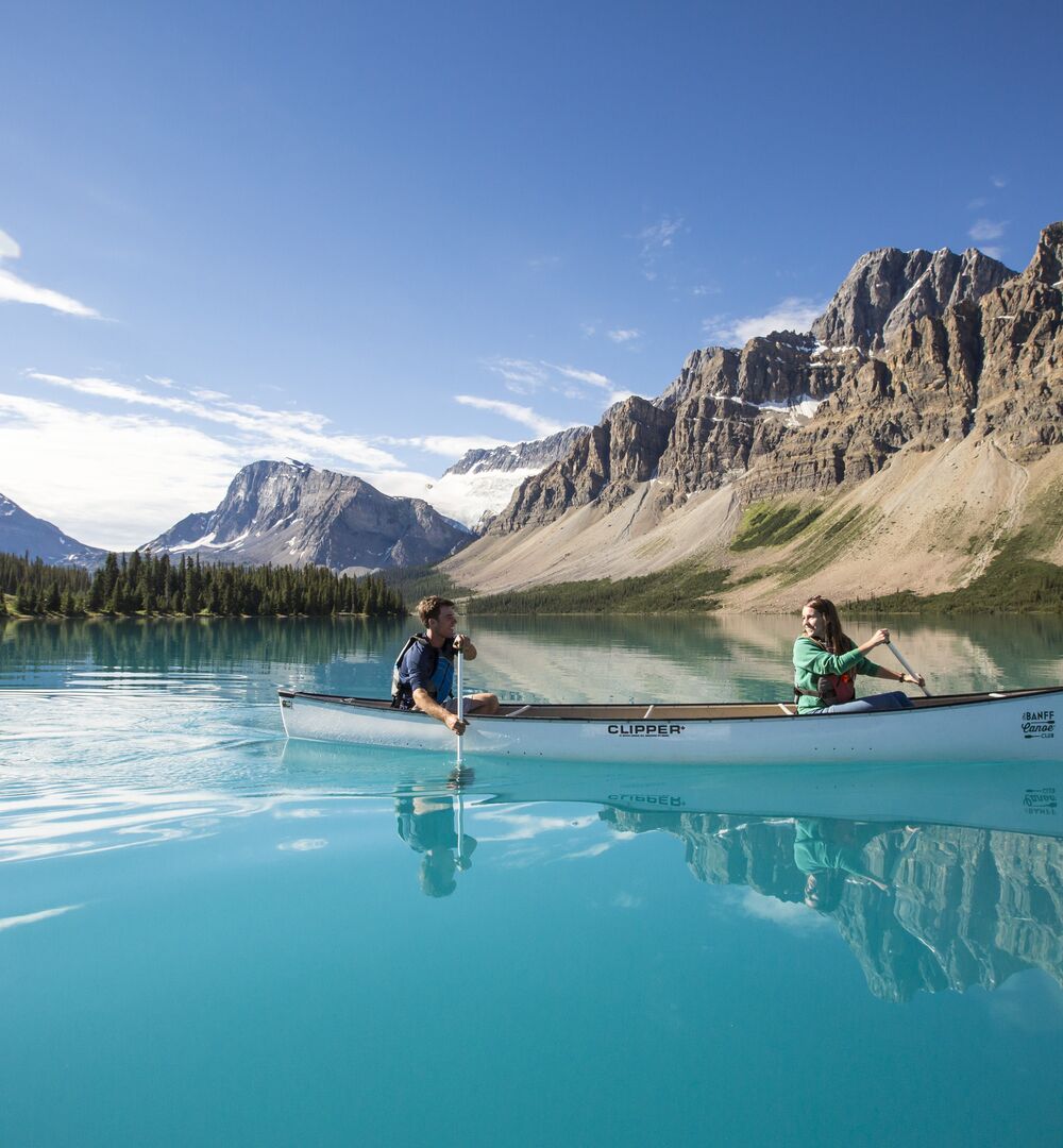 People paddling in a canoe on the turquoise waters of Bow Lake in the summer